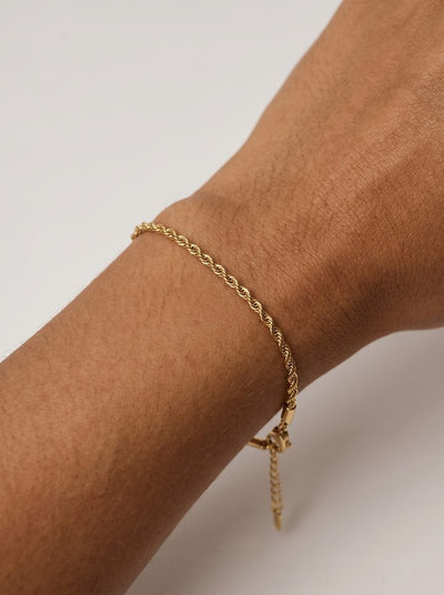 Close-up of a gold twisted rope bracelet on a warm-toned wrist