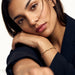 Anchor Twist Chain Bracelet – worn on the wrist, head resting on the arm at a table, gold, dark blazer, ivory studio background