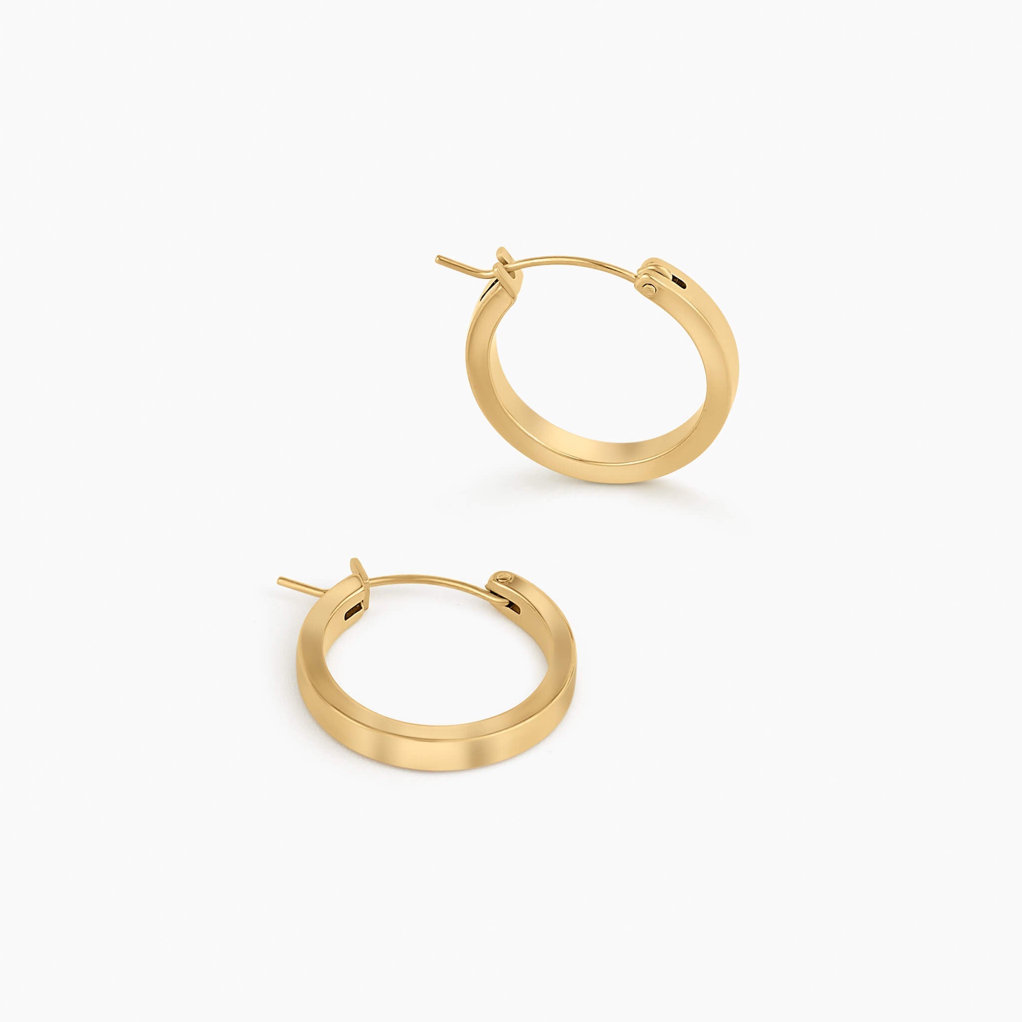 Crossing Hoops in gold, pair of thin wire hoop earrings flat lay