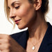 Dawn Pearl Pendant Necklace – side view, looking down, mother-of-pearl pendant on the chest, navy blazer, ivory studio background