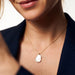 Dawn Pearl Pendant Necklace – close crop of a smile and the mother-of-pearl pendant, navy blazer, ivory studio background