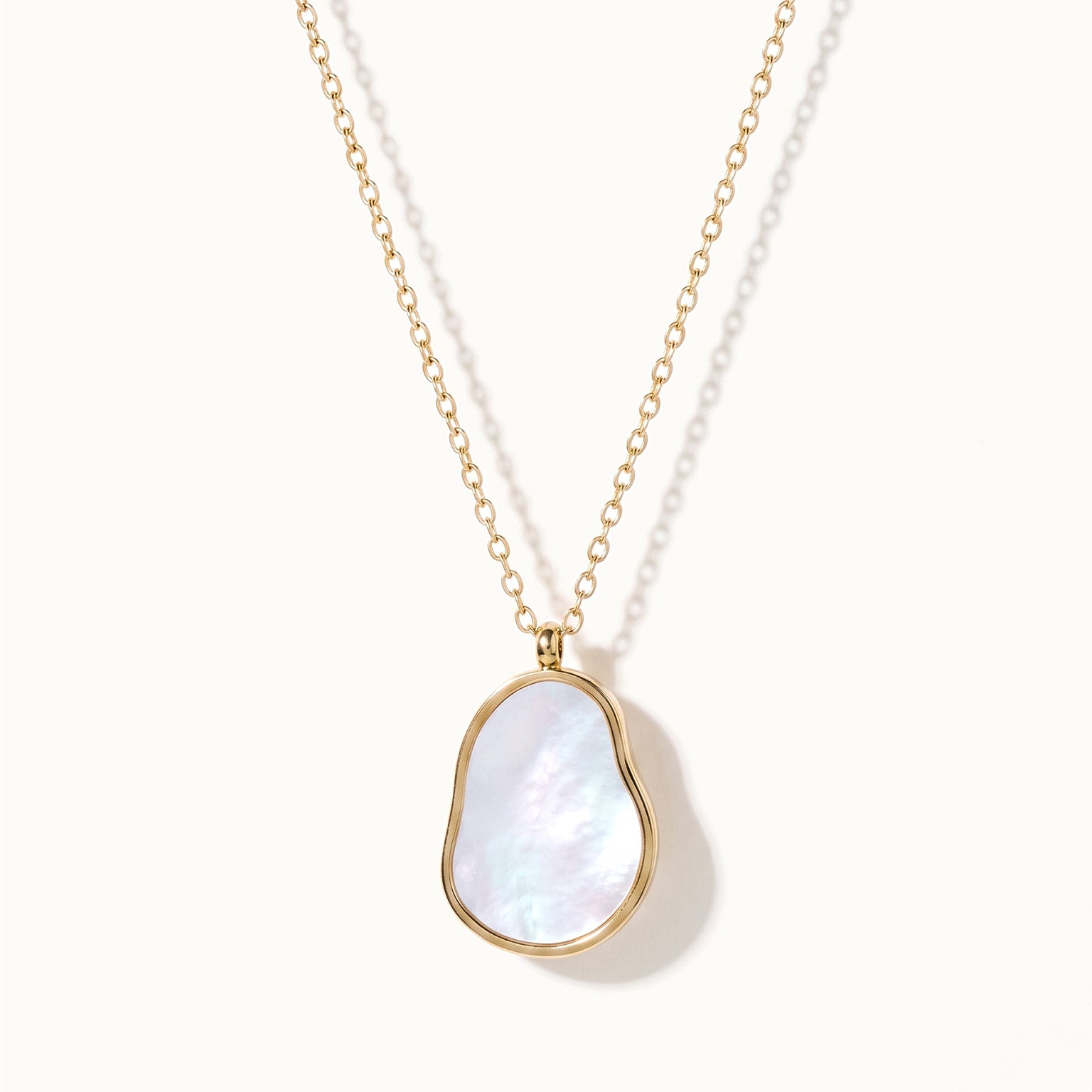 Dawn Pearl Pendant Necklace – mother-of-pearl pendant hanging on a fine chain, gold, on ivory background