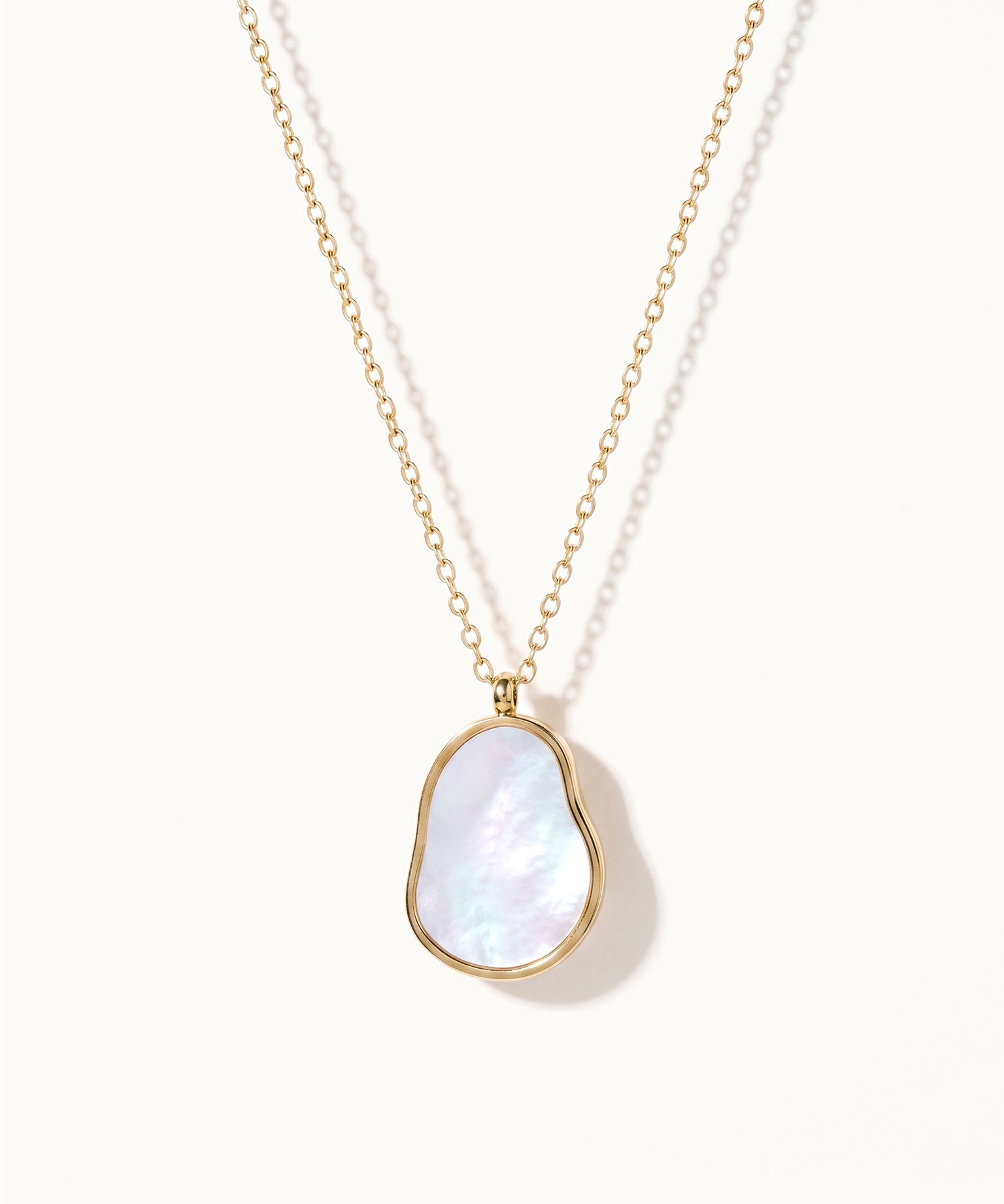 Dawn Pearl Pendant Necklace – mother-of-pearl pendant hanging on a fine chain, gold, on ivory background