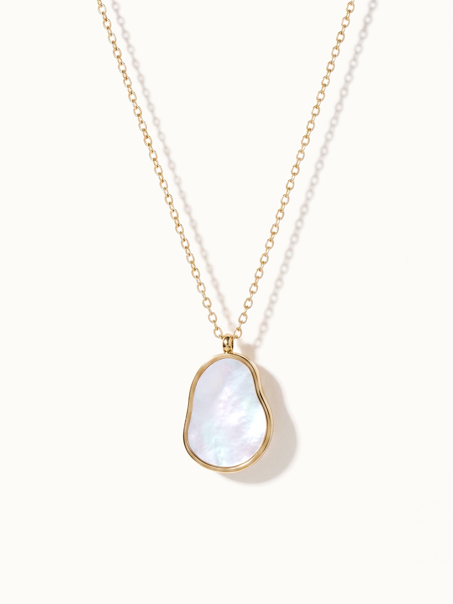 Dawn Pearl Pendant Necklace – mother-of-pearl pendant hanging on a fine chain, gold, on ivory background