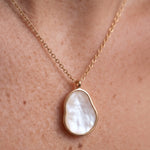 Dawn Pearl Pendant Necklace – close-up of the mother-of-pearl pendant against the skin, gold