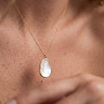 Dawn Pearl Pendant Necklace – worn at the base of the neck, hand at the chest, gold, mother-of-pearl pendant