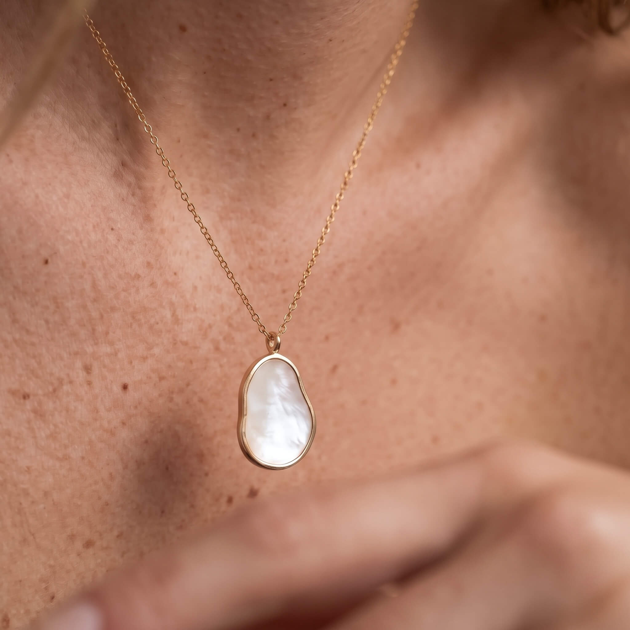 Dawn Pearl Pendant Necklace – worn at the base of the neck, hand at the chest, gold, mother-of-pearl pendant