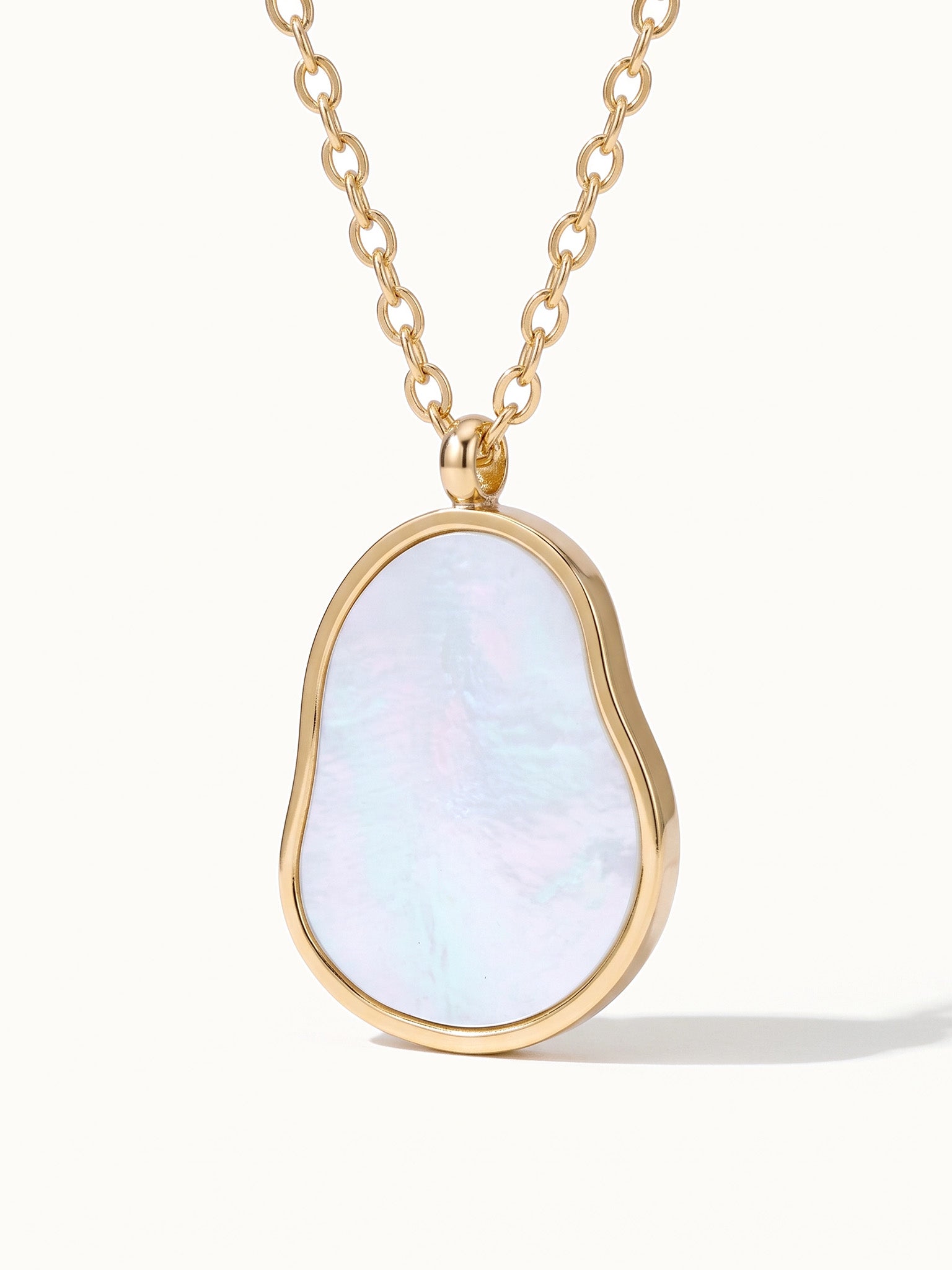 Dawn Pearl Pendant Necklace – close-up of the mother-of-pearl pendant and chain, gold, on ivory background
