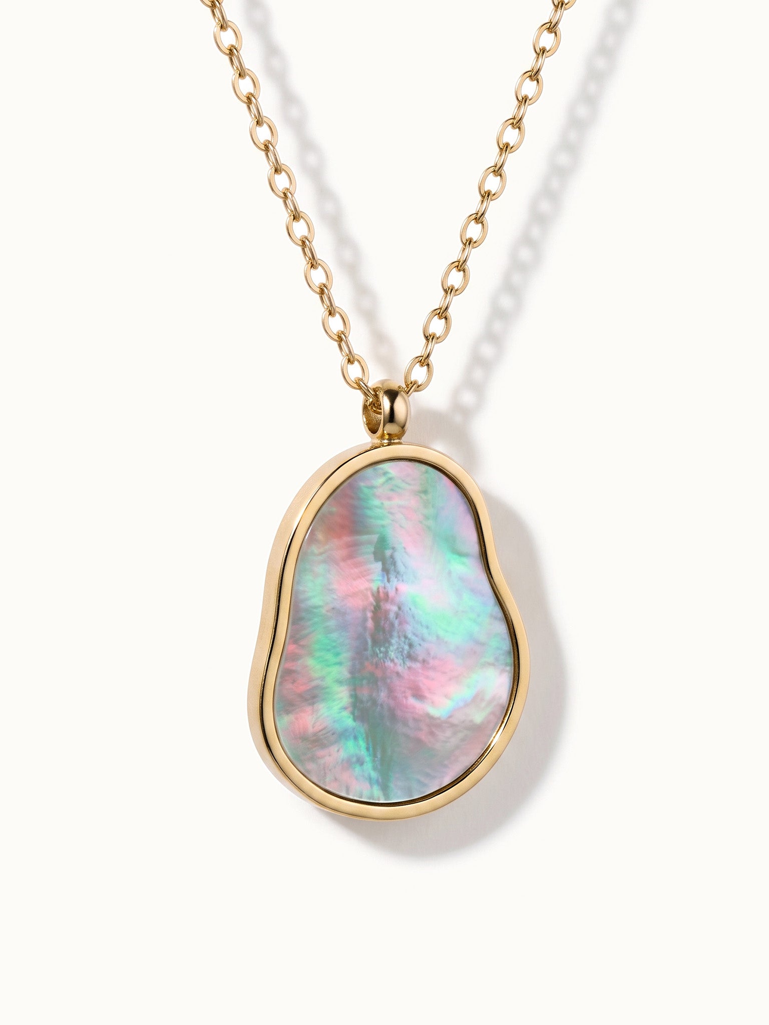 Dawn Pearl Pendant Necklace – close-up of the pendant with pink and green iridescence, gold, on ivory background