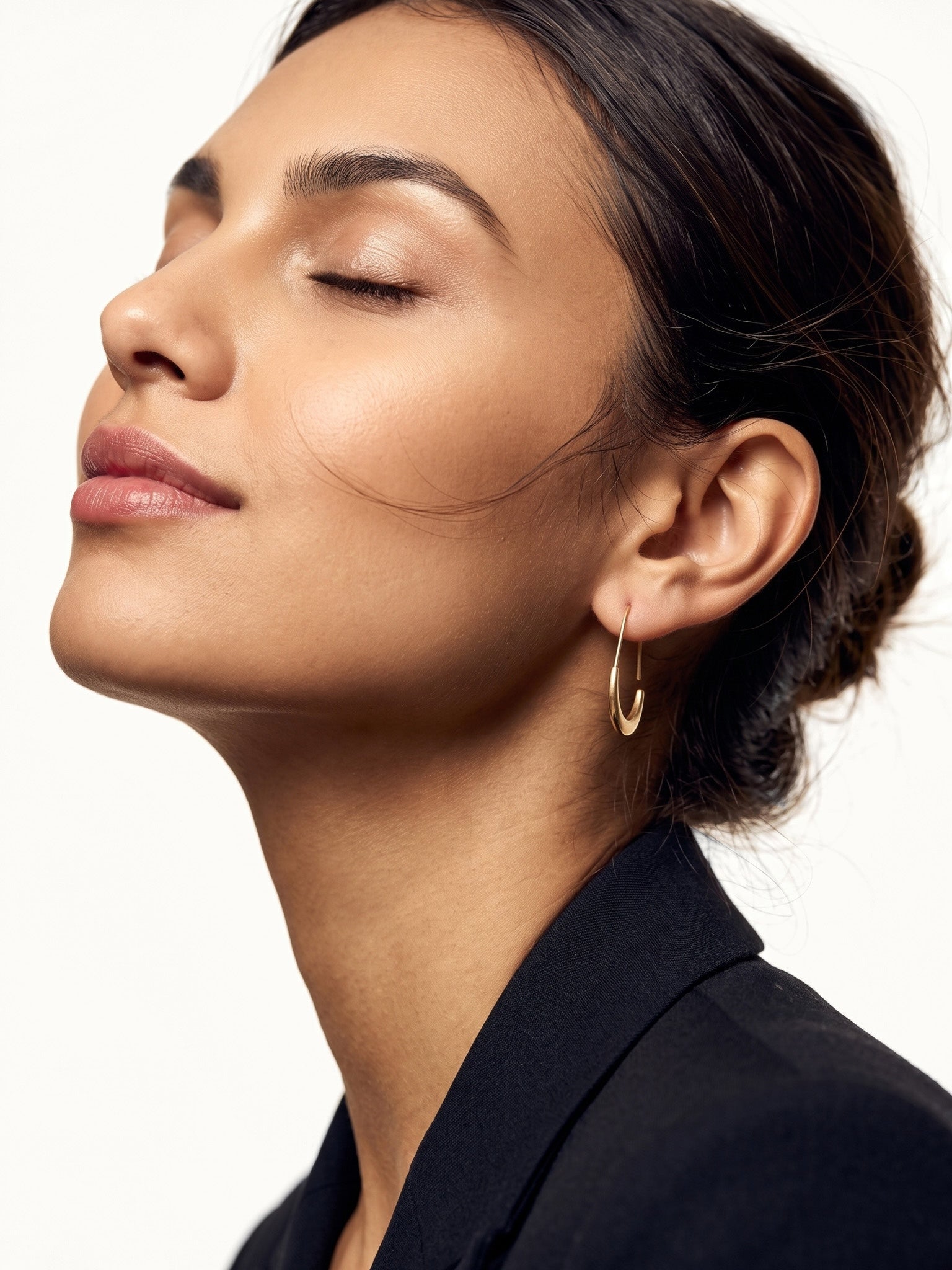 Evening Grace Drop Earrings – worn in the ear, head tilted back with eyes closed in side view, gold, dark blazer, hair in a low bun