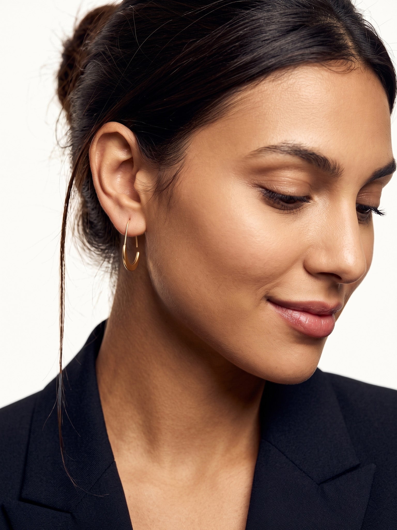 Evening Grace Drop Earrings – worn in the ear, looking down with a soft smile, gold, hair tied back