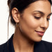 Evening Grace Drop Earrings – worn in the ear, looking down with a soft smile, gold, hair tied back