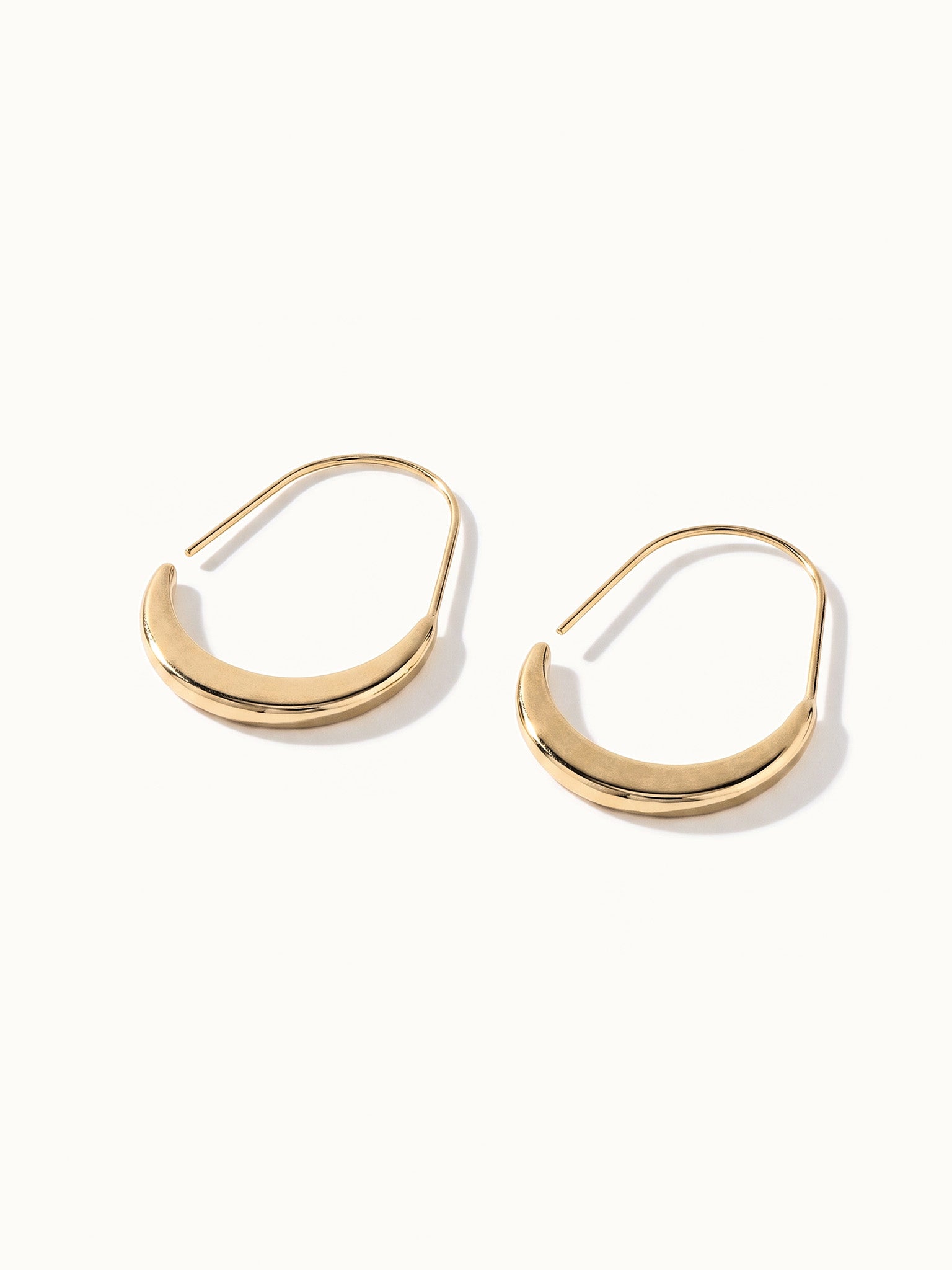 Evening Grace Drop Earrings – pair of tapered drop hoops, lying flat, gold, on ivory background
