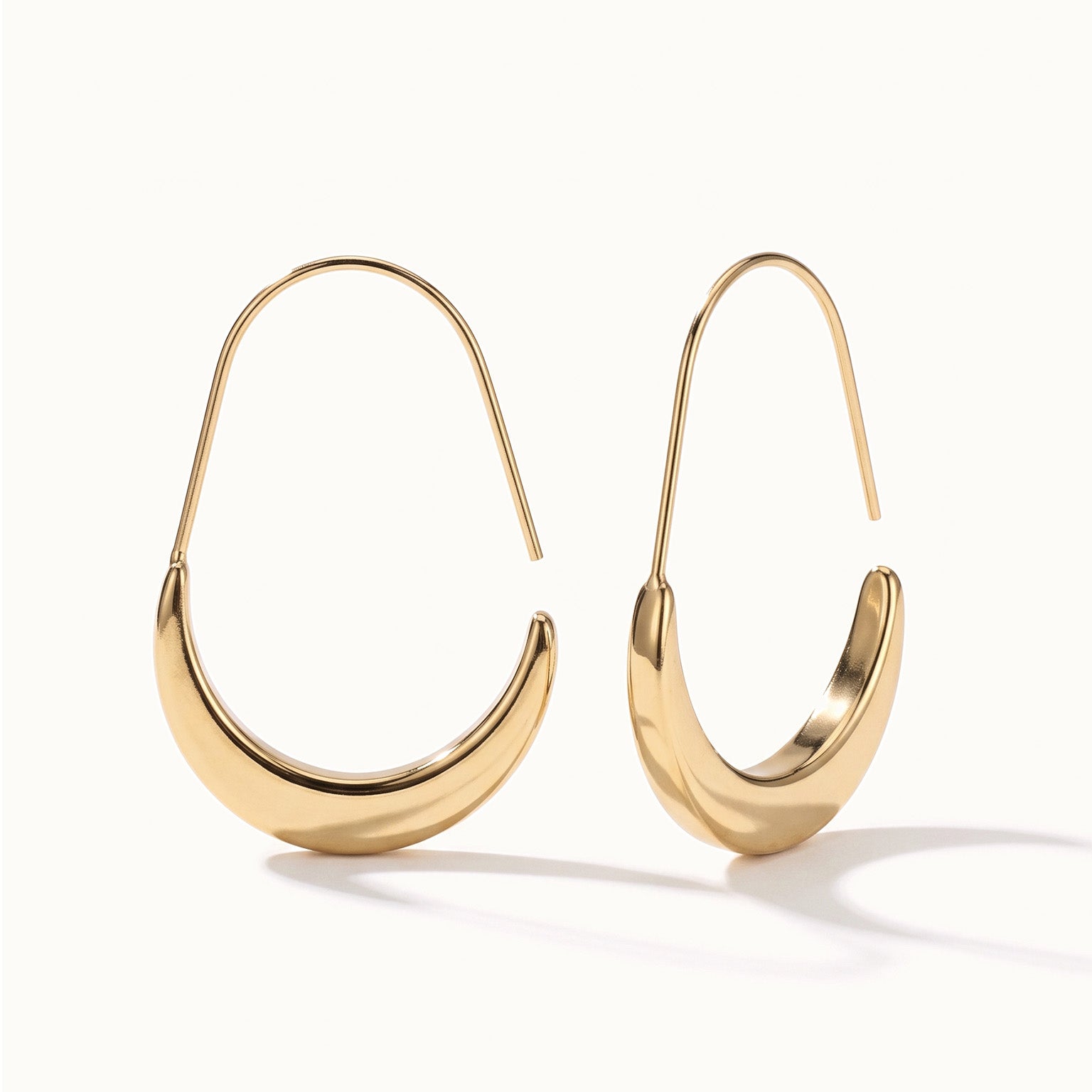 Evening Grace Drops – pair of tapered drop hoops, standing upright, gold, on ivory background