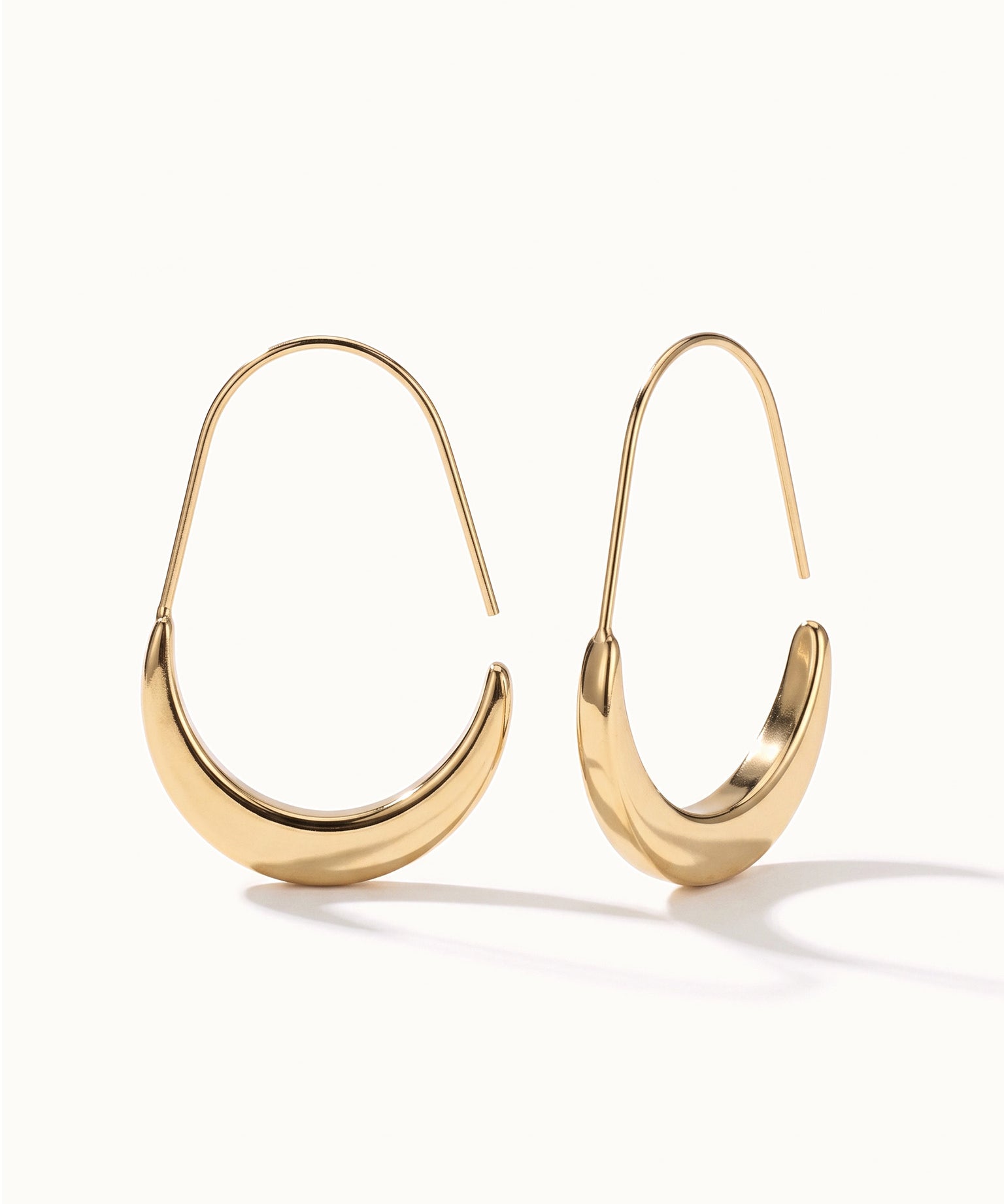 Evening Grace Drops – pair of tapered drop hoops, standing upright, gold, on ivory background