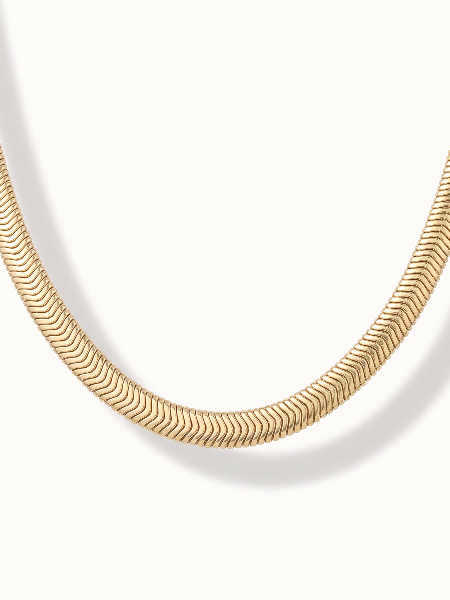 Everlasting Chain Necklace – close-up of the flat snake chain at the bottom of the curve, gold, on ivory background