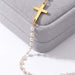 Every Season Cross Necklace – gold cross and pearls draped over a grey velvet Fallen Season box