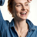 Everyday Loop Necklace – gold loop pendant on a fine chain, laughing model with one hand resting on her head, blue denim shirt, ivory studio background