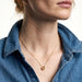 Everyday Loop Necklace – gold loop pendant on a fine chain, model with her face turned to one side, blue denim shirt, ivory studio background