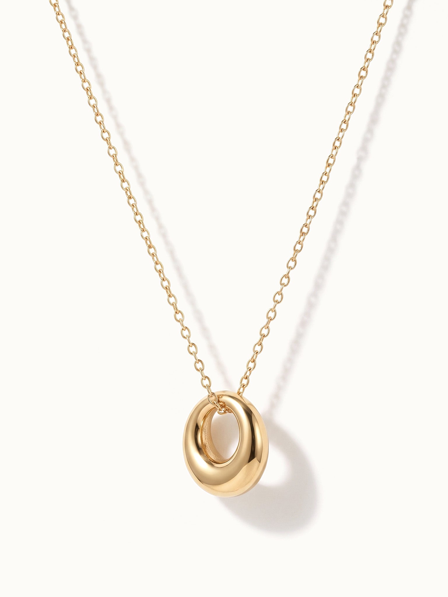 Everyday Loop Necklace – loop pendant hanging on a fine chain, turned to the side, gold, on ivory background