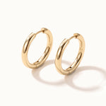 Faithful Hoops – pair of plain polished hoops, angled view, gold, on ivory background