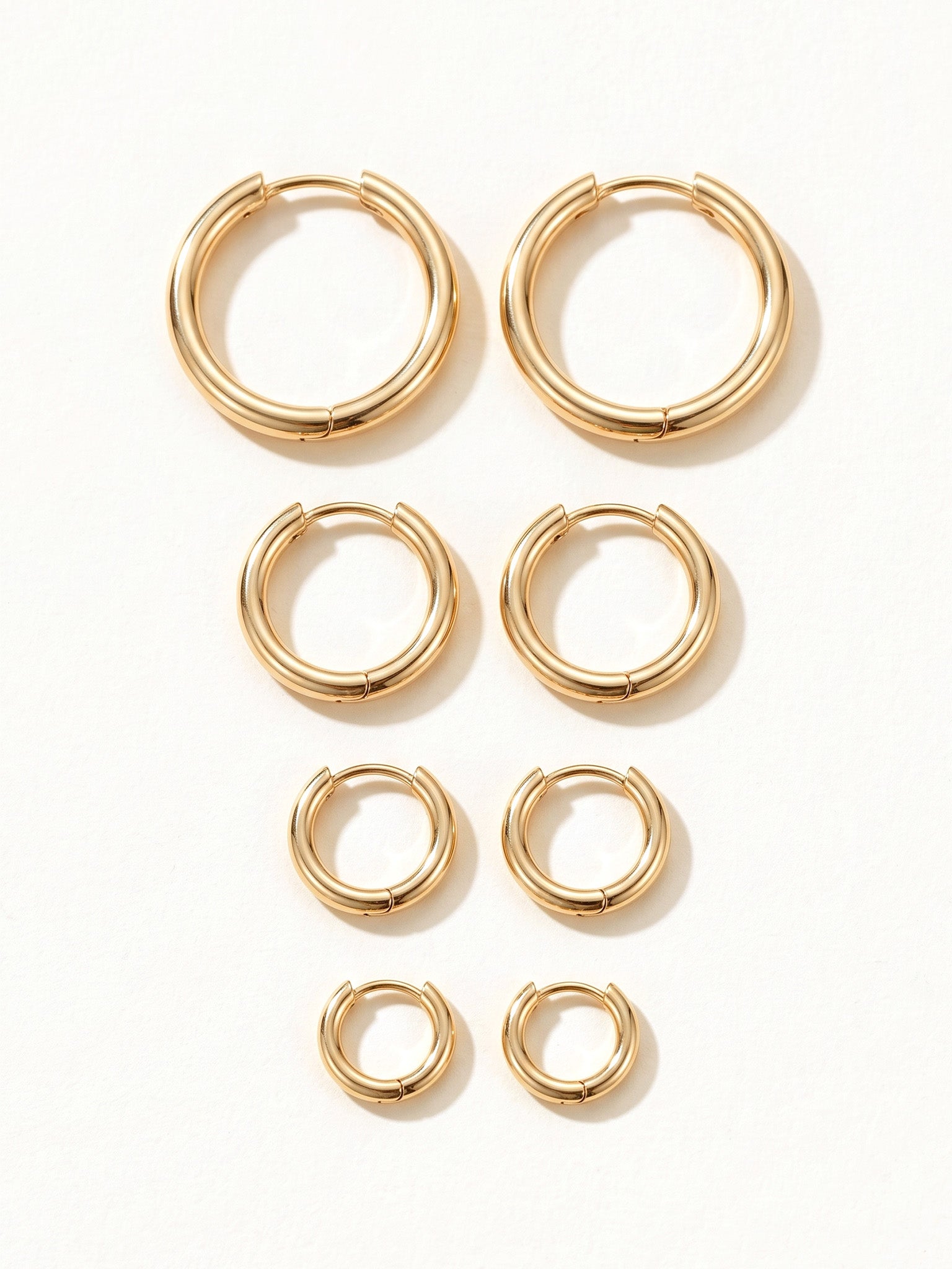 Faithful Hoops – all four sizes lying flat, 12mm to 6mm, gold, on ivory background