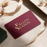 Fallen Season gift card in burgundy and gold foil, styled with dried flowers and ribbon