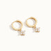 Field Lily Drop Earrings – pair of flower drop huggie hoops, lying flat, gold, on ivory background