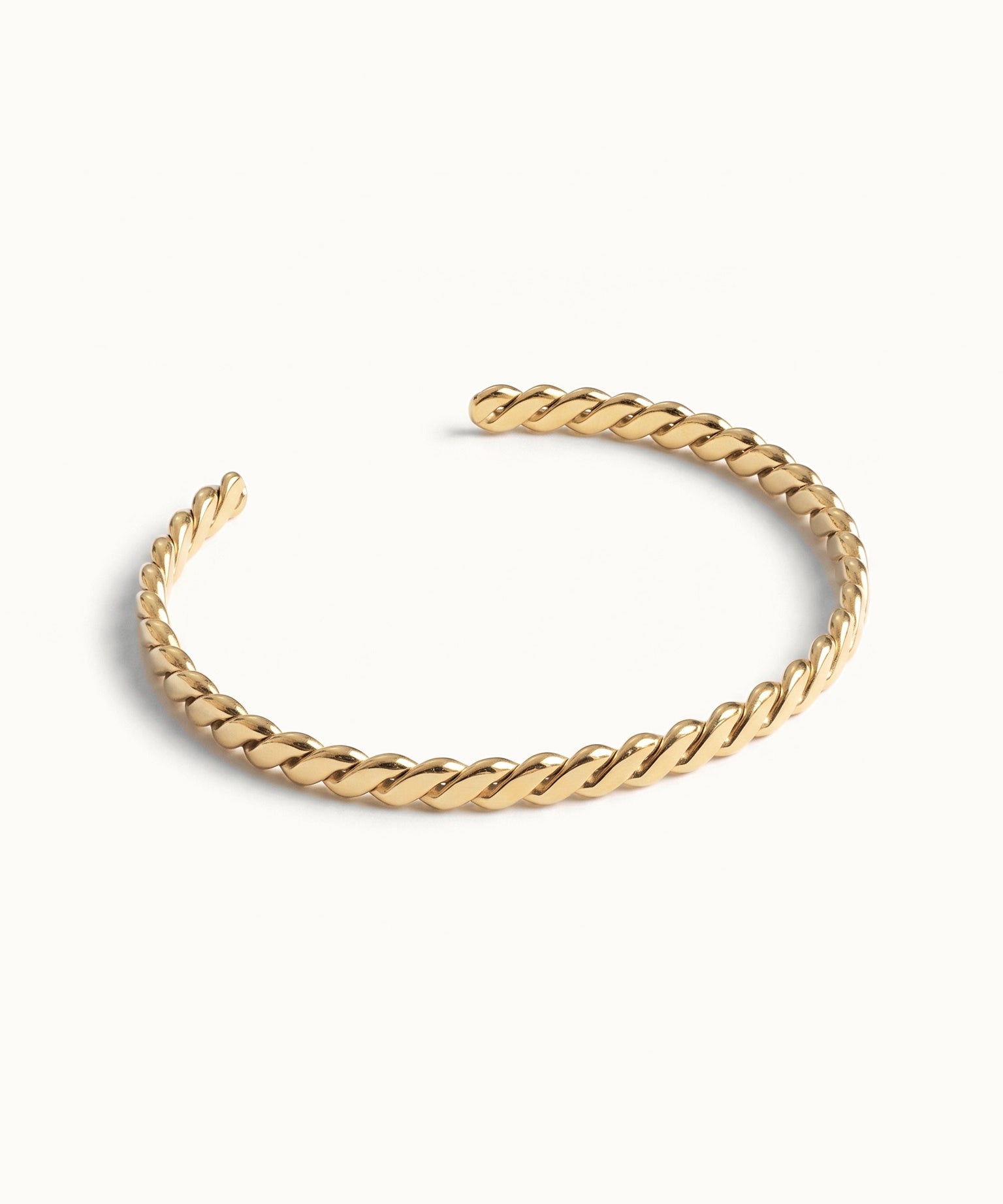 Fire & Roots Cuff – rope-twist cuff, angled view, gold, on ivory background