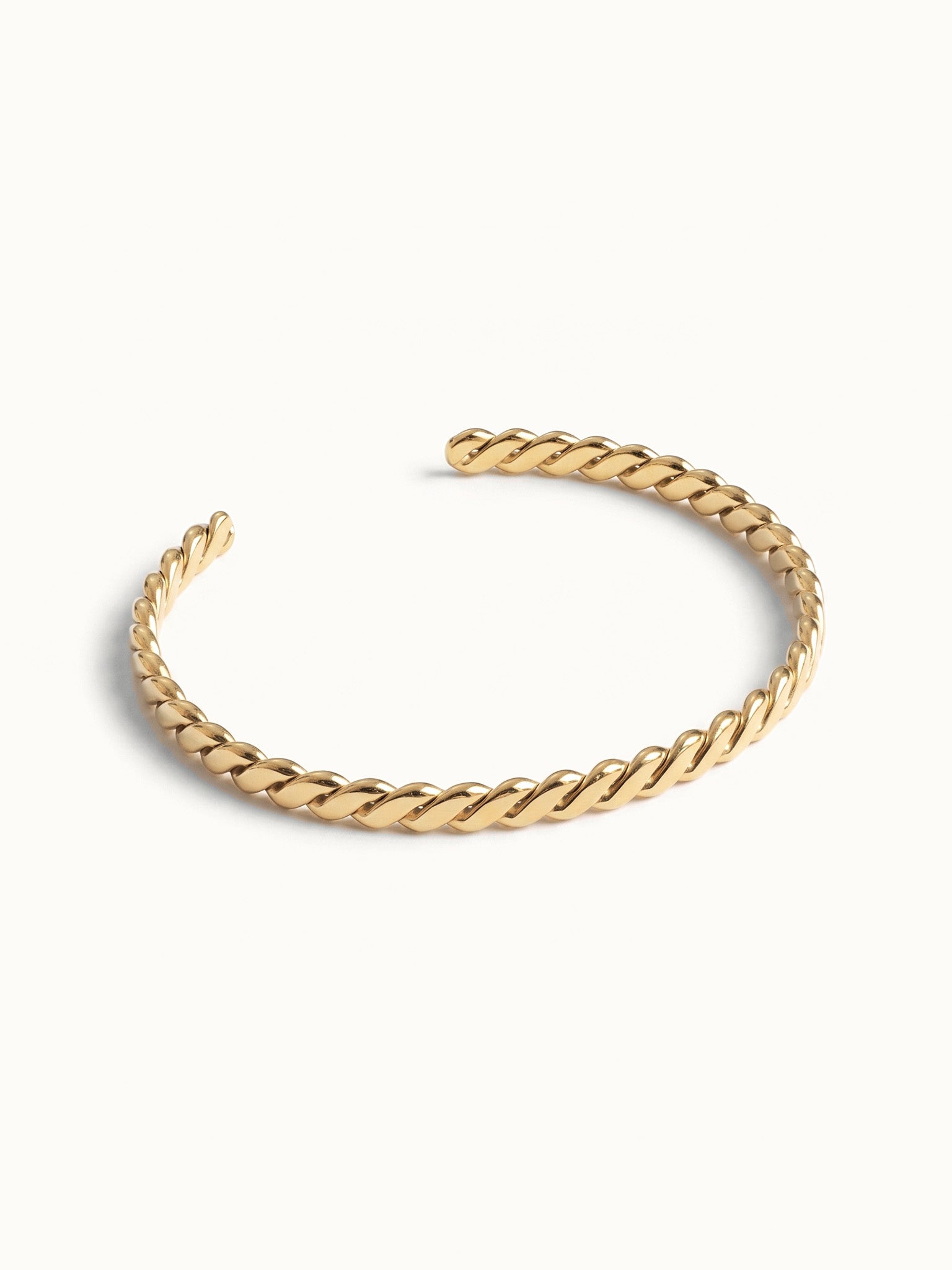 Fire & Roots Cuff – rope-twist cuff, angled view, gold, on ivory background