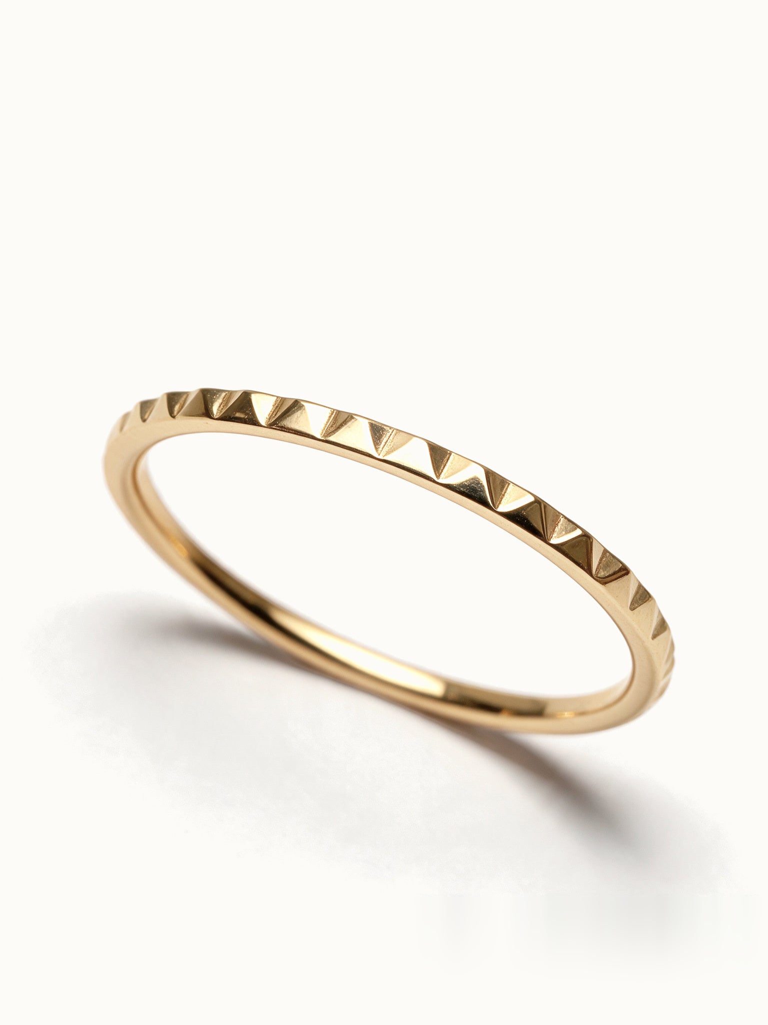 Fire Band – close-up of the faceted edge, gold, on ivory background