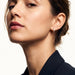 Four Seasons Huggies – worn in the ear, head tilted back with chin lifted, gold four-stone huggie, dark hair up
