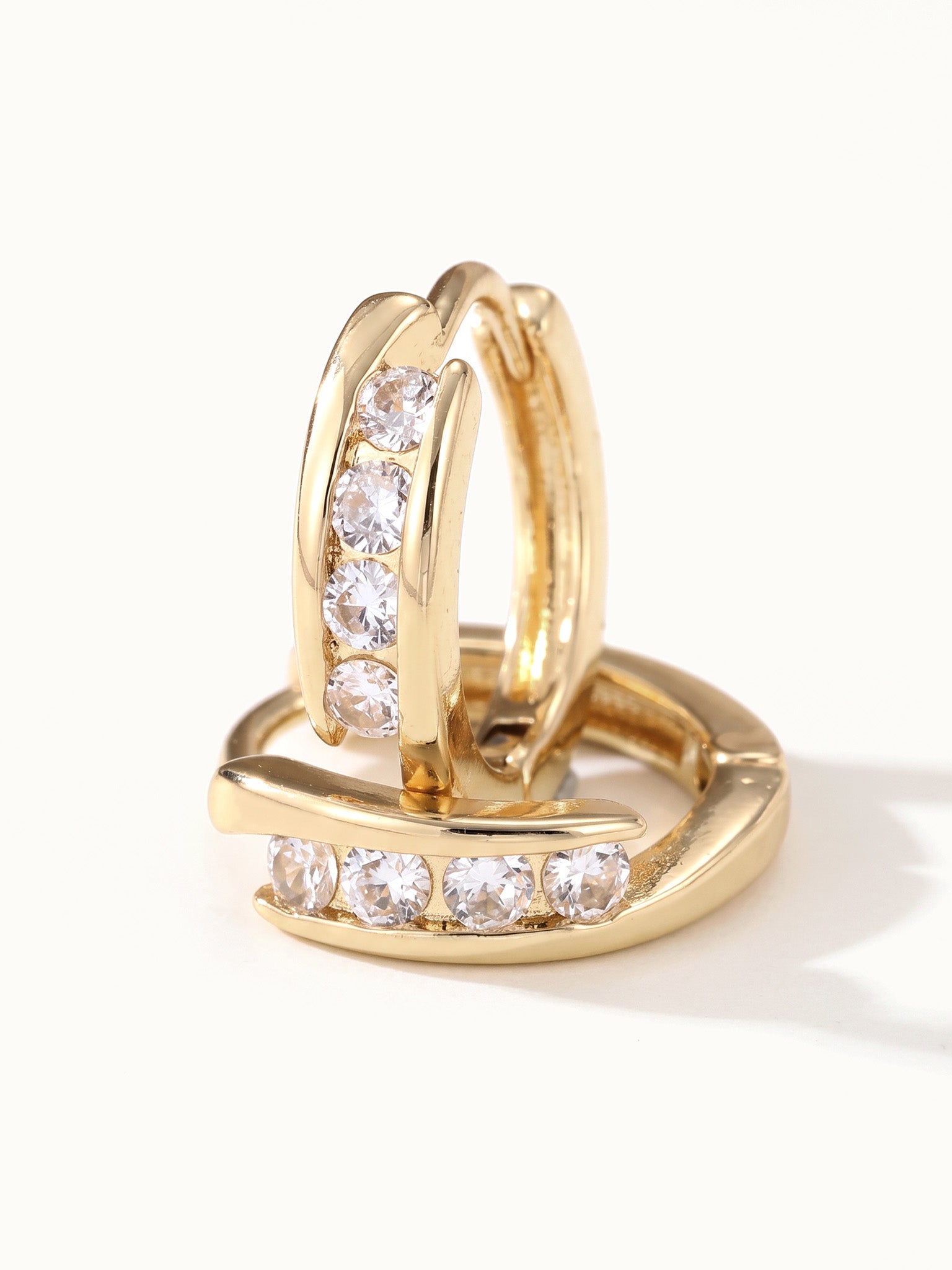 Four Seasons Huggies – close-up of the four-stone huggie hoops, gold, on ivory background