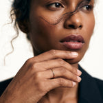 Golden Season Band – worn with fingertips at the chin, gold, dark blazer, ivory studio background
