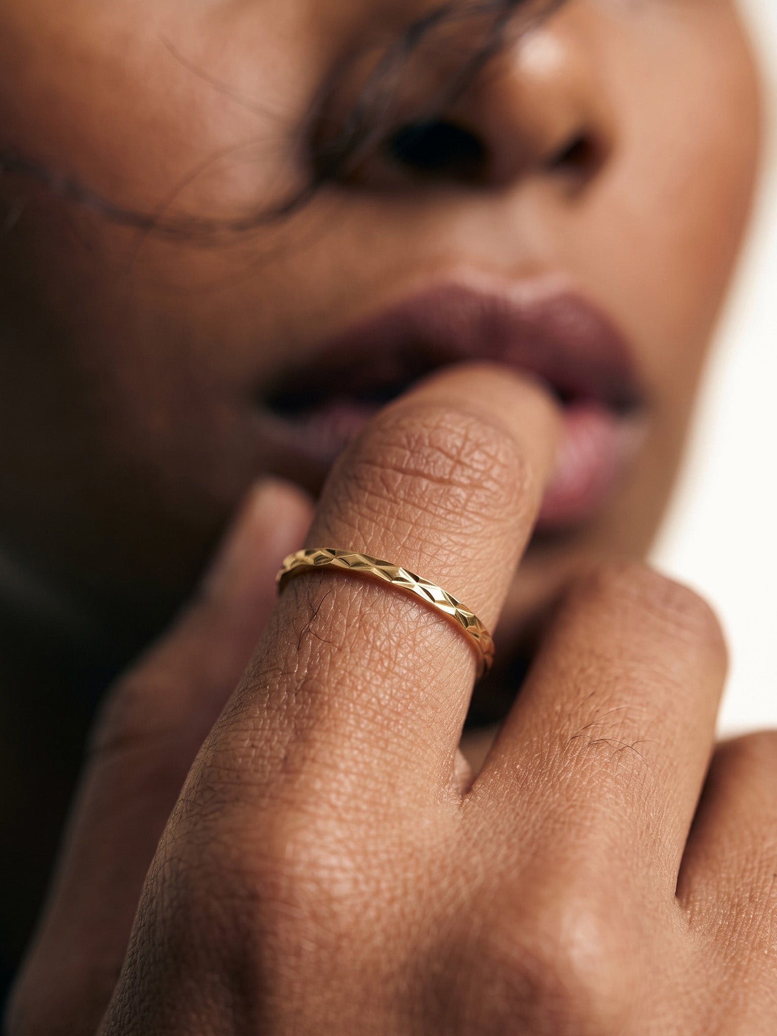 Golden Season Band – worn with a finger raised to the lips, gold, close-up