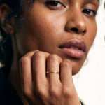 Golden Season Band – worn with the hand at the chin, gold, dark top, ivory studio background