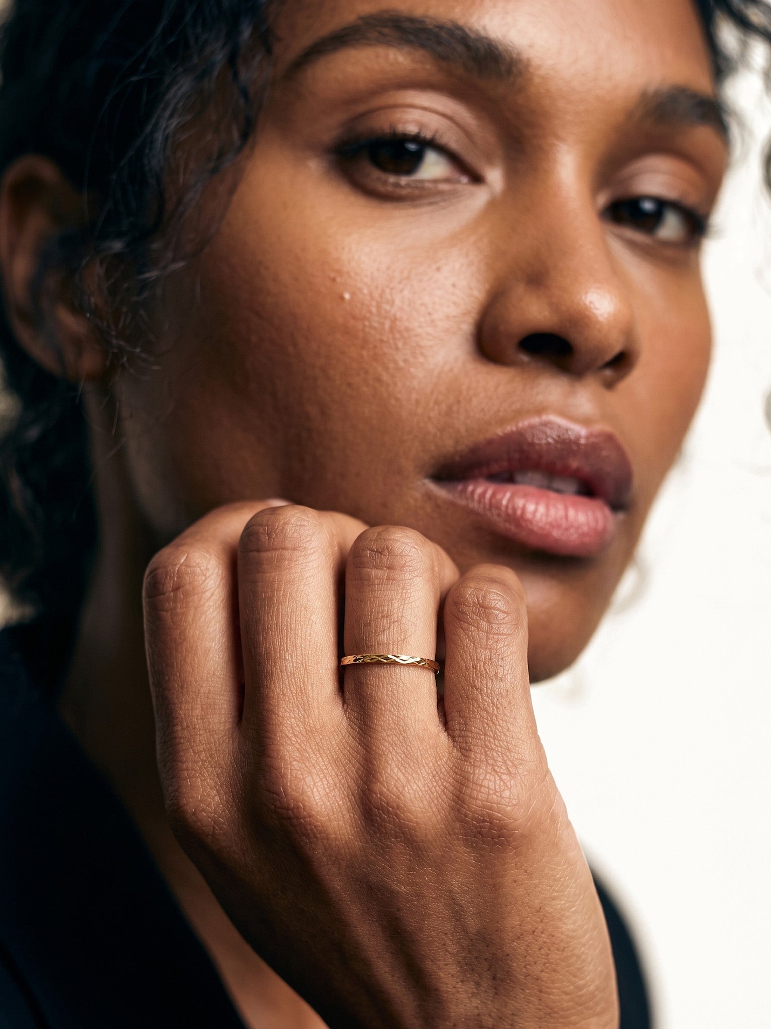Golden Season Band – worn with the hand at the chin, gold, dark top, ivory studio background