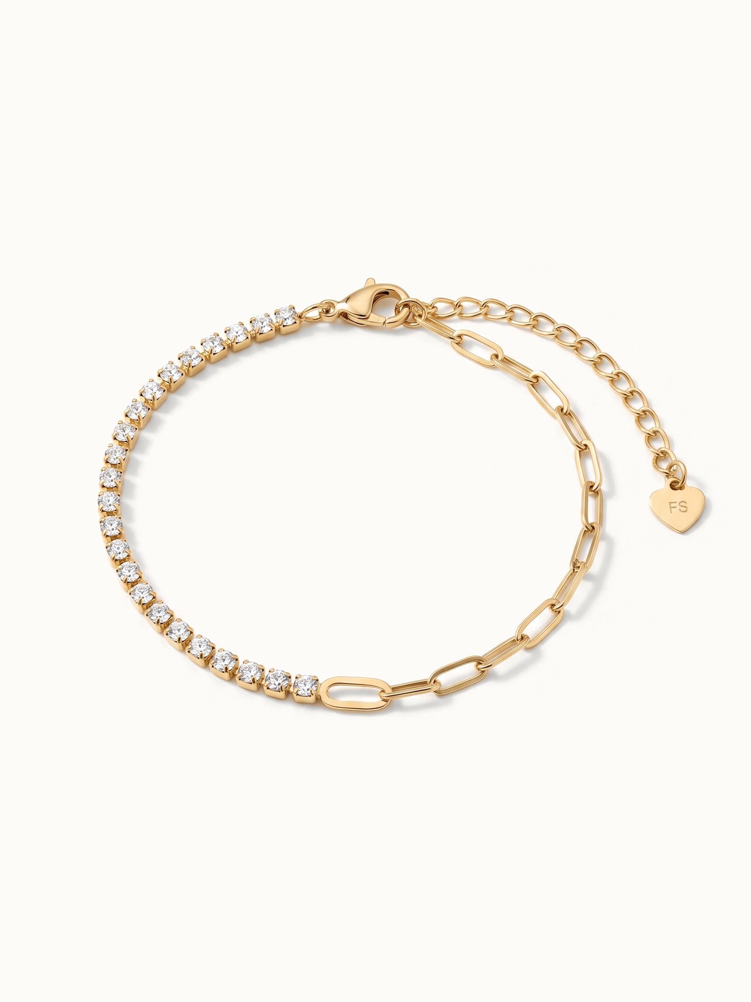 Grace Line Bracelet – crystal row at the front with paperclip links and heart charm, angled view, gold, on ivory background