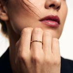 Grace Stack Ring – worn on a hand raised to the cheek, gold, dark blazer, ivory studio background