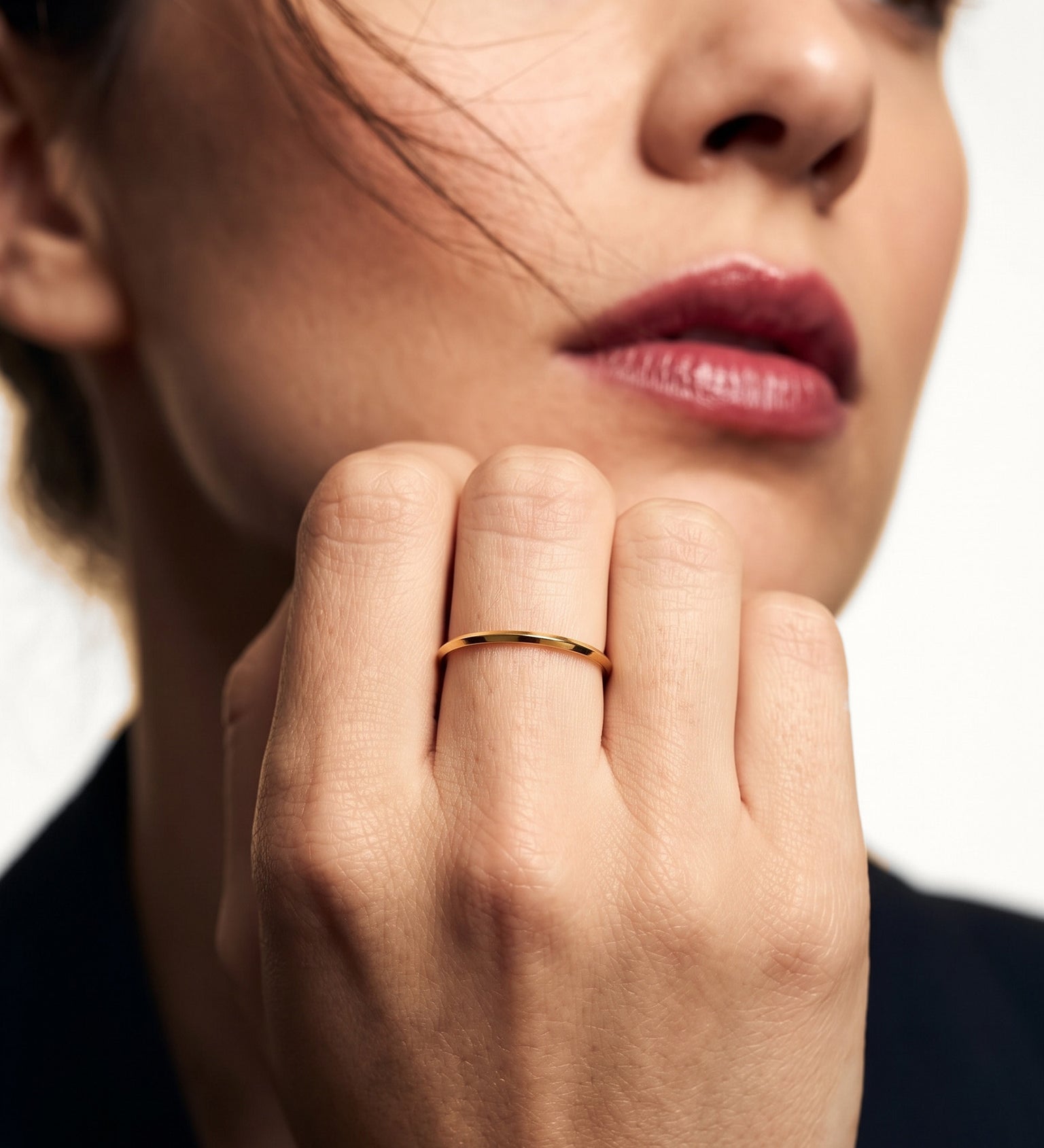 Grace Stack Ring – worn on a hand raised to the cheek, gold, dark blazer, ivory studio background
