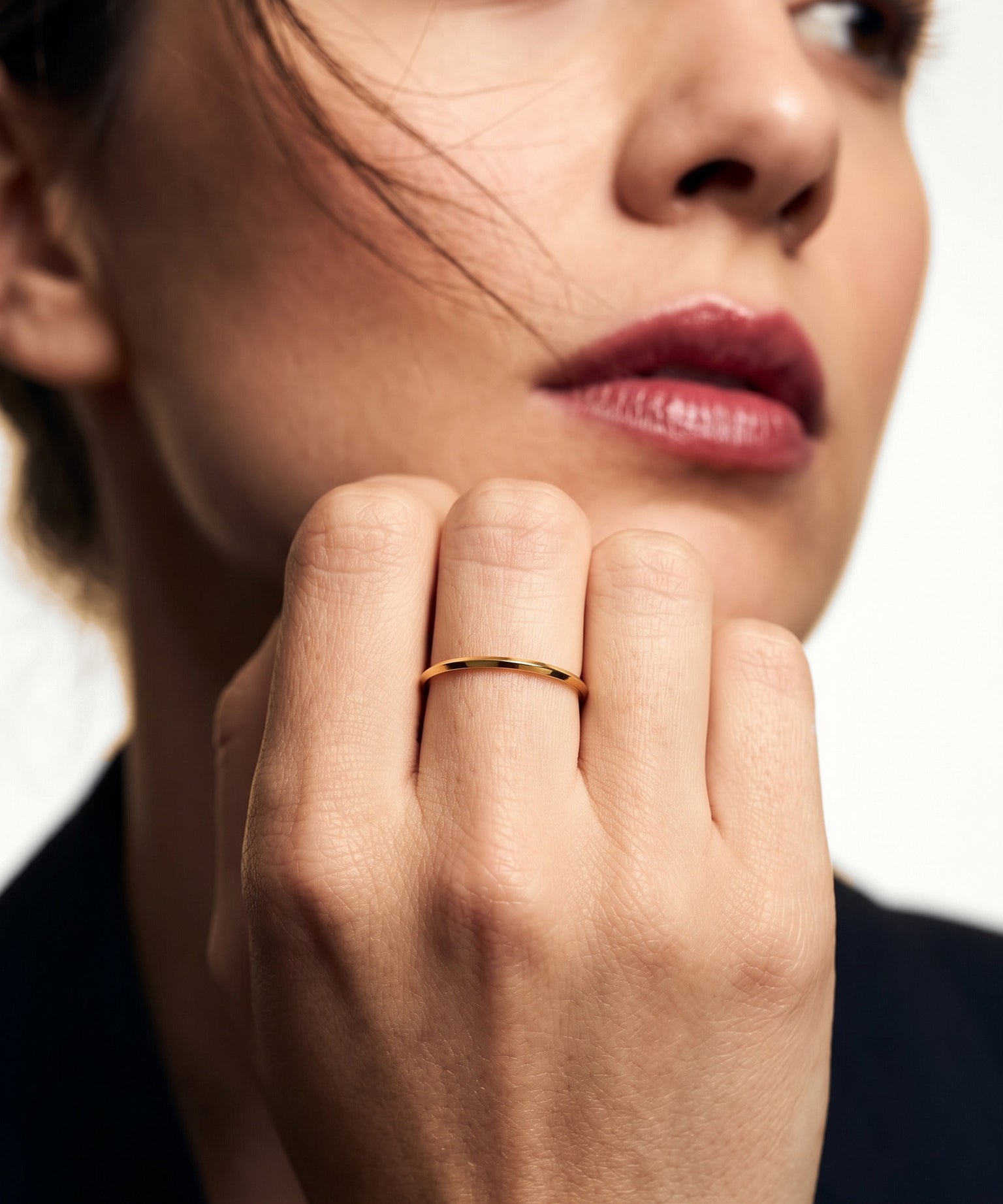 Grace Stack Ring – worn on a hand raised to the cheek, gold, dark blazer, ivory studio background