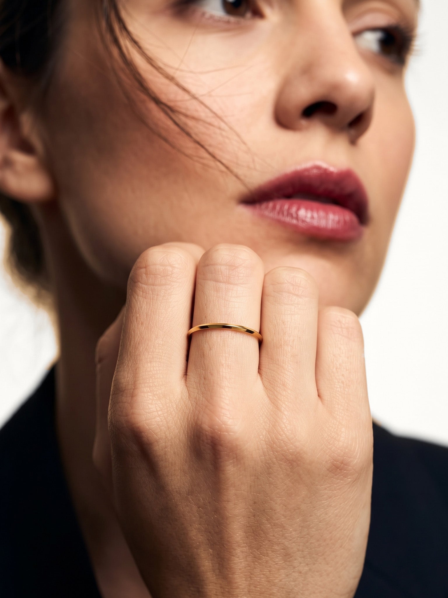 Grace Stack Ring – worn on a hand raised to the cheek, gold, dark blazer, ivory studio background