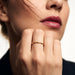 Grace Stack Ring – worn on a hand raised to the cheek, gold, dark blazer, ivory studio background
