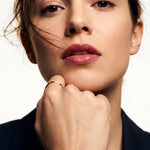 Grace Stack Ring – worn on a closed hand beneath the chin, gold, dark blazer, ivory studio background