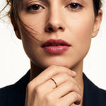 Grace Stack Ring – worn with fingers resting at the chin, gold, front view, ivory studio background
