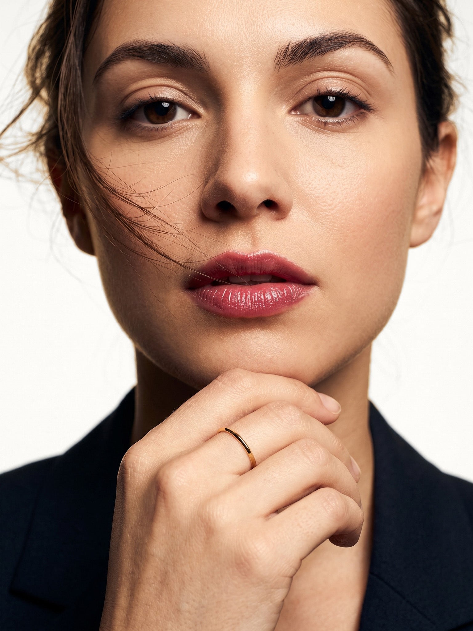 Grace Stack Ring – worn with fingers resting at the chin, gold, front view, ivory studio background