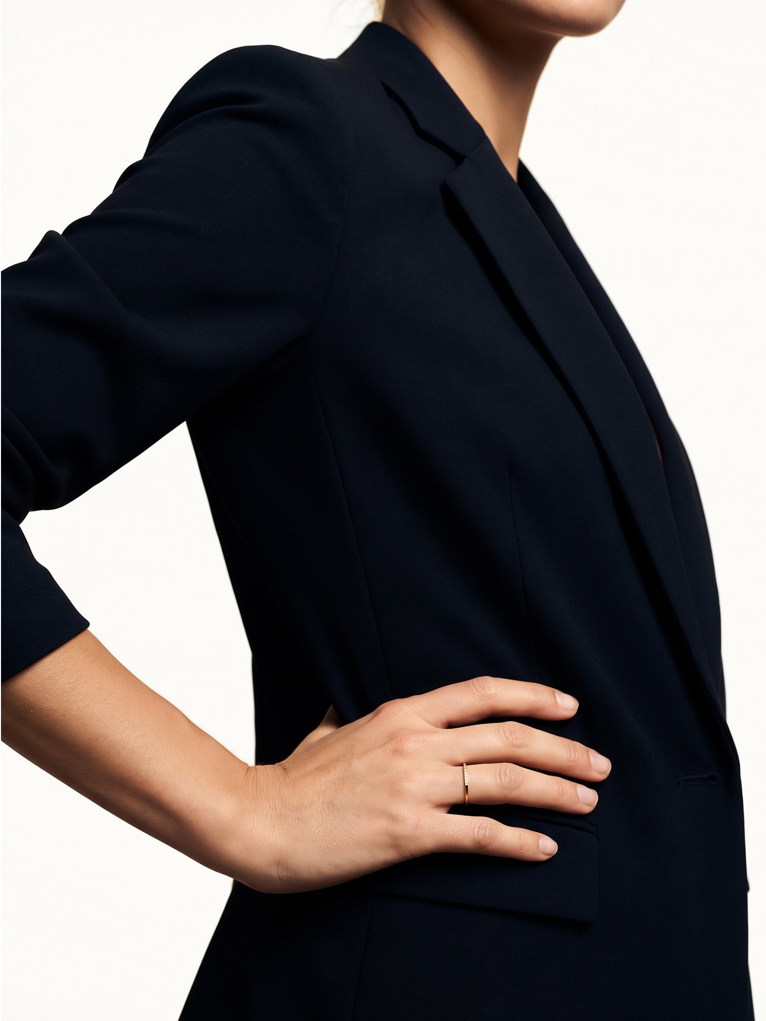 Halo Band Ring – worn with the hand resting on the hip, gold, dark blazer, ivory studio background