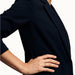 Halo Band Ring – worn with the hand resting on the hip, gold, dark blazer, ivory studio background