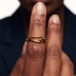 Held Ring – worn on fingers raised in front of the lips, close-up, gold, dark blazer, ivory studio background
