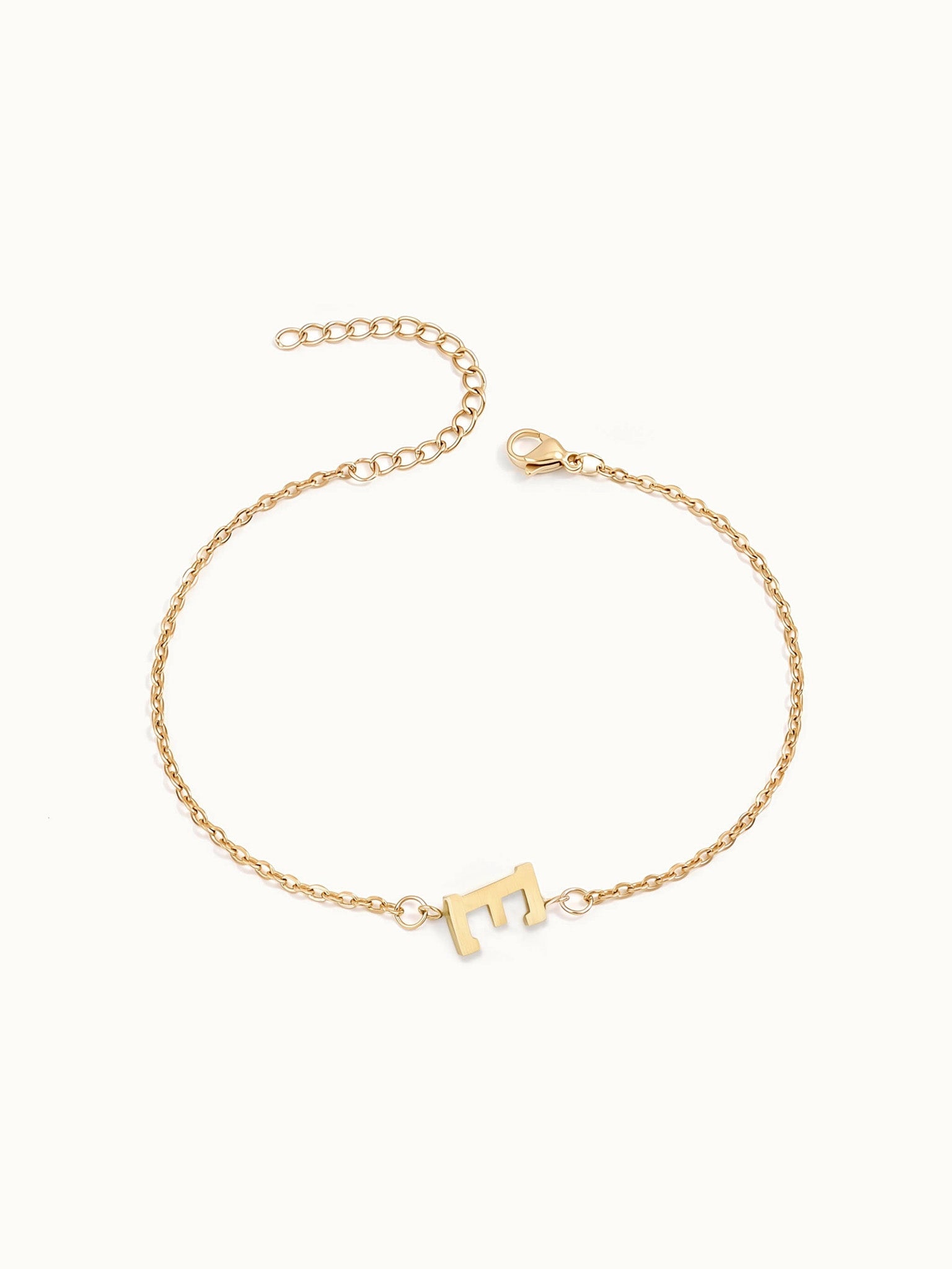 Initial Bracelet – letter E charm on a fine cable chain, gold, on ivory background